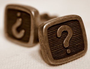 Image: a pair of cufflinks with question marks on them.