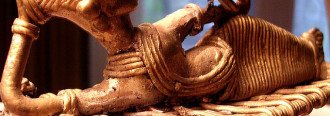 An image of a Central Indian tribal figuring of a woman reclining and reading a book.