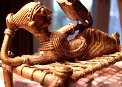 An image of a Central Indian tribal figuring of a woman reclining and reading a book.