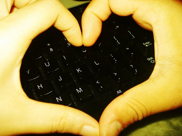 Hands forming a heart symbol over a keyboard