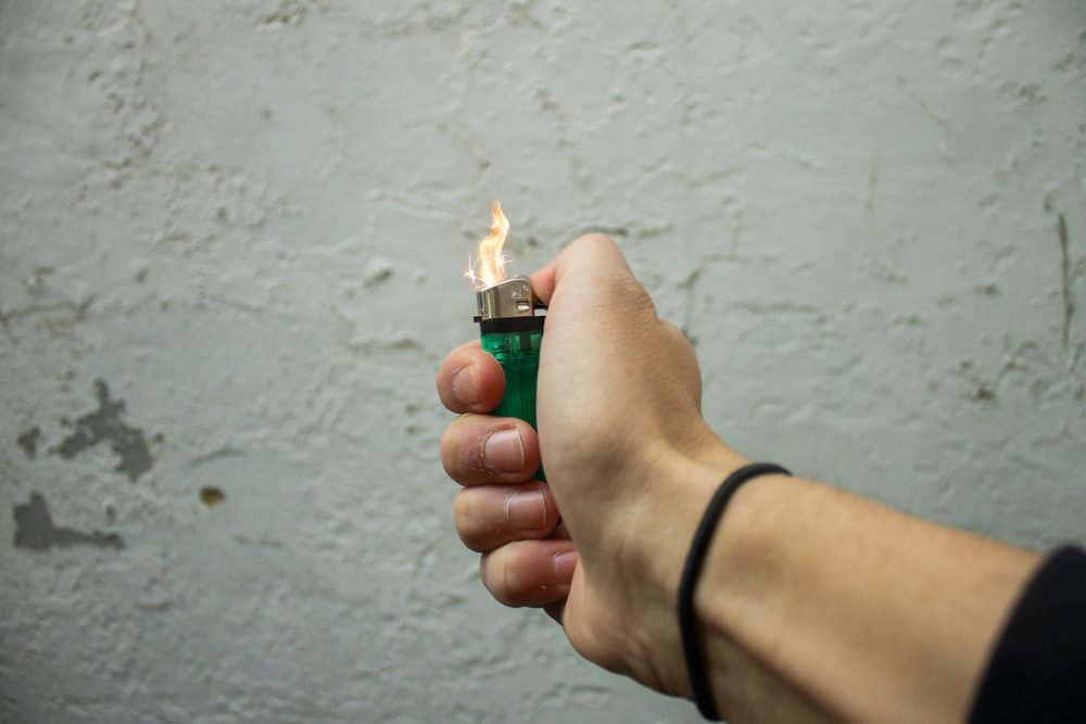 Image: woman's hand sparking a disposable lighter