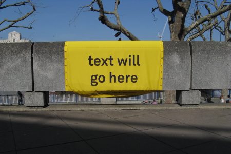 Image: a sign printed with the words "text will go here," draped over a wall
