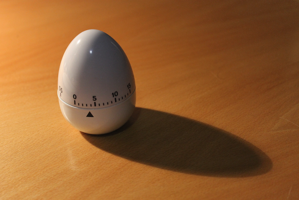 Image: an egg-shaped kitchen timer, set to four minutes, sits on a table.