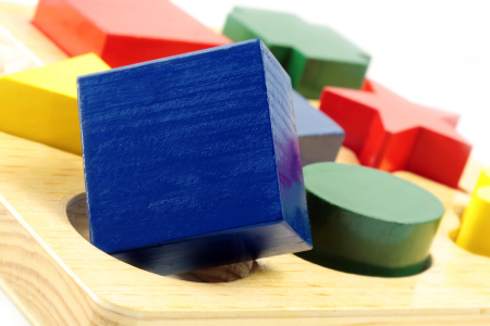 Image: in a set of children's multi-colored toy blocks, a blue wooden cube is unable to fit into a round hole.