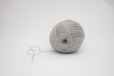 Image: a gray ball of yarn sits on a white background.