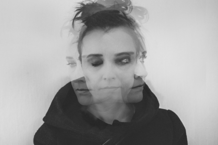 Image: a triple-exposed black and white photograph of a woman's face, turned to left, right, and center.