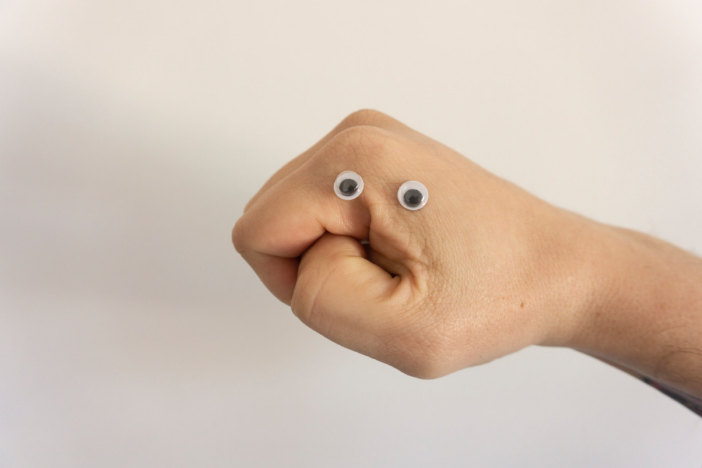 Image: a clenched hand with two googly eyed applied, to resemble a face.