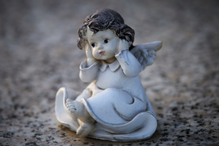 Image: a small statuette of a "hear no evil" cherub holding its hands over its ears.