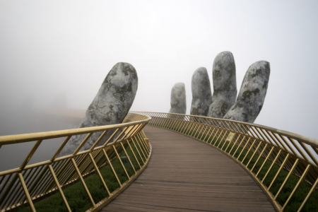 Image: The Golden Bridge near Da Nang, Vietnam. Amid heavy fog, an enormous sculpted hand supports the walkway which curves and disappears into the distance.