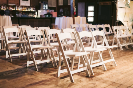Image: rows of empty, wooden folding chairs are lined up for an event.