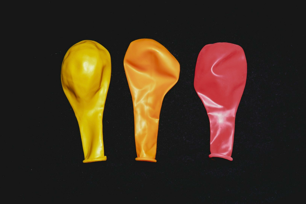 Image: three uninflated party balloons lie on a black background.