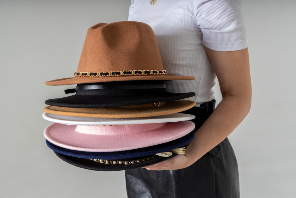 Image: a woman holds a stack of different hats