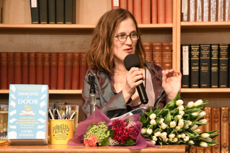 Image: author Laura Stanfill speaks into a microphone at the launch event for her new book Imagine a Door on April 1, 2025 at Powell's City of Books in Portland, Oregon.