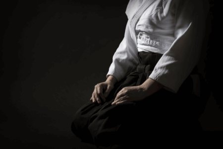 Image: a female martial artist sits in quiet preparation in a darkened room.