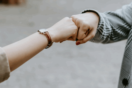 Image: two women's hands engaged in a fist bump