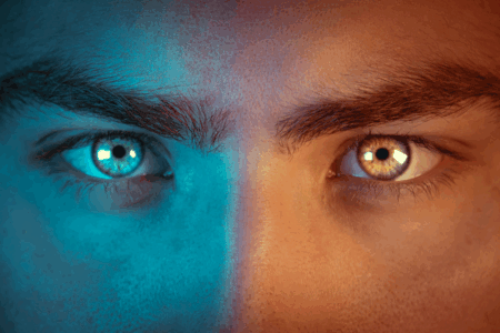 Image: close-up of a man's eyes, his left side lit normally but his right side lit in blue as if to imply a second, more chilling personality.