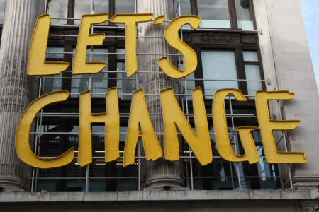 Image: On the front of an elegant old urban building is a modern sign reading "Let's Change".