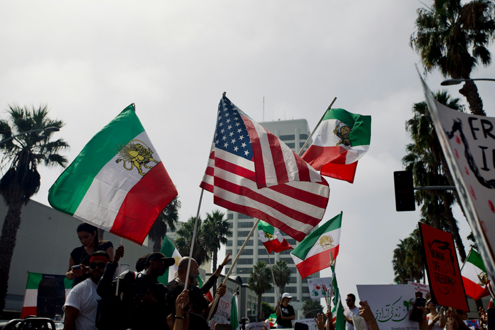Image: At an outdoor protest for Iranian freedom, people wave both American and Iranian flags.