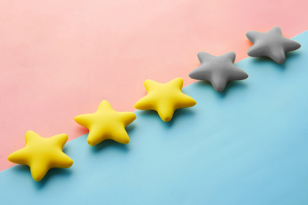 Image: against a backdrop that's pink on one half and blue on the other half, five injection-molded rubber stars are lined up in a row: three of the stars are yellow, and the remaining two are gray.