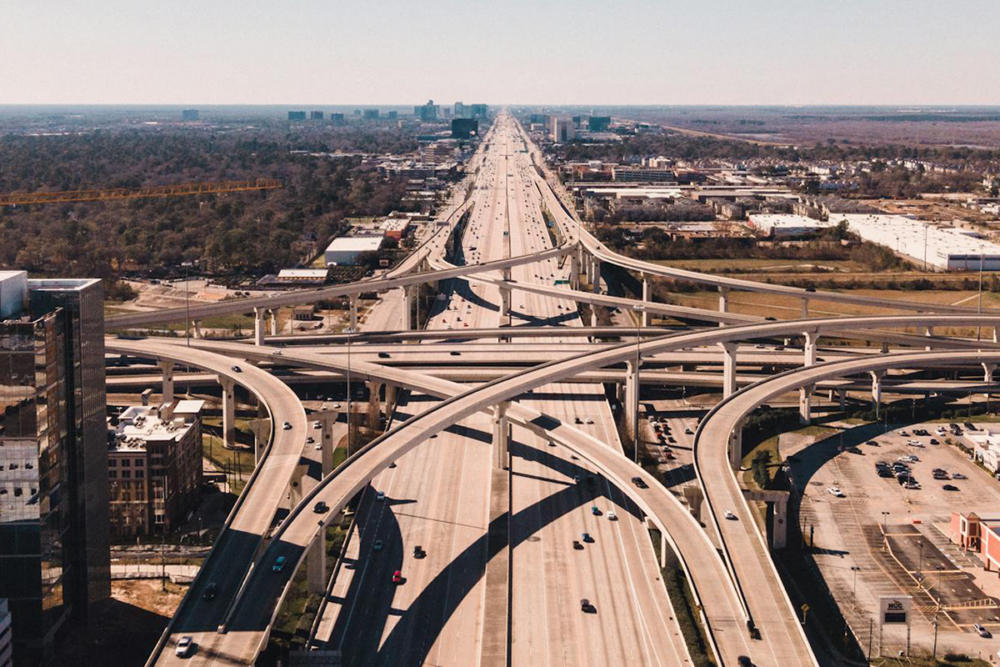 Image: aerial view of the Houston, Texas I-10 highway interchange of numerous criss-crossing ramps above the main highway.
