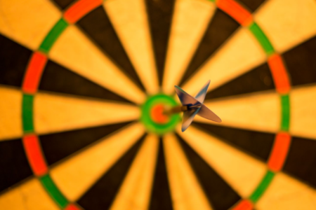 Image: a single dart has struck the bullseye of a dartboard